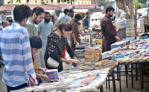 People are engaged in selecting and buying old books from the weekly stalls on the roadside of Mall Road.