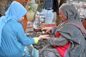 A woman vendor applies mehndi on a customer's hand at her setup near Wazir Ali Road.