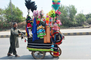 A hawker pushes his cart displaying with beautiful and colorful truck decorations and accessories to attracting customers for sale at Hala Naka Road.