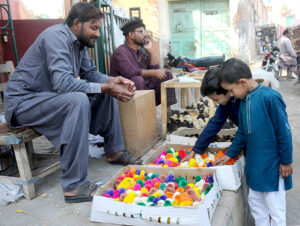 Children are buying colorful chicks from a vendor at a roadside setup