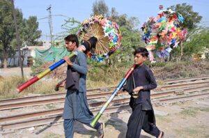 Street vendors passing by railway track to sell sweet item for children.