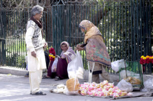 A disabled lady vendor selling edible items to a customer at Qasim Bagh Road.