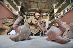 A man busy in making wooden decoration pieces at his workplace near Tehsil area.