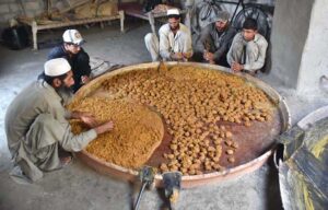 Laborers busy in preparing traditional sweet item "Gur" at his workplace near Naguman area.