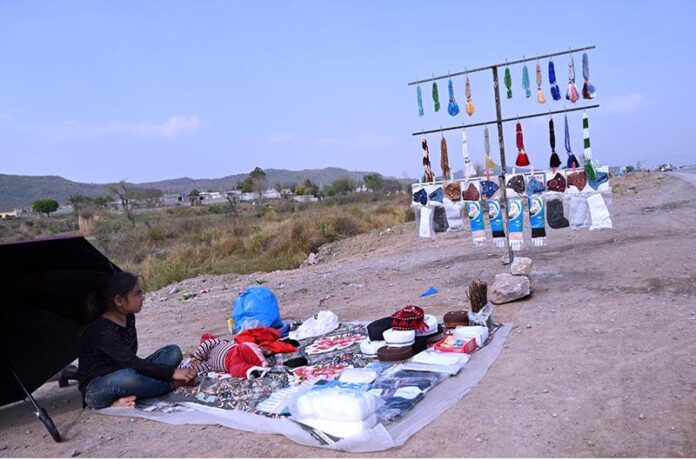 Little girl vendor sells tasbeeh and caps on the roadside near Chak Shahzad during the holy month of Ramadan in the Federal Capital