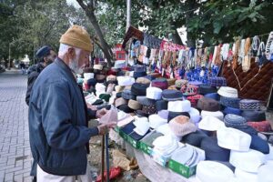 An aged man selects and purchase cap on a roadside stall during holy fasting month of Ramadan at Aabpara in the Federal Capital