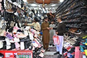 A person purchasing shoes from a shop in Aabpara Market as people shopping for preparation of upcoming Eidul Fitr