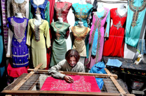 A craftsman is busy embroidering women's clothing in Shahi Bazaar as demand for fancy dresses for the upcoming Eid al-Fitr is high.