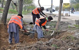 Workers diligently clean the green belt along Srinagar Highway in the Federal Capital for new plantation ahead of the coming spring season.