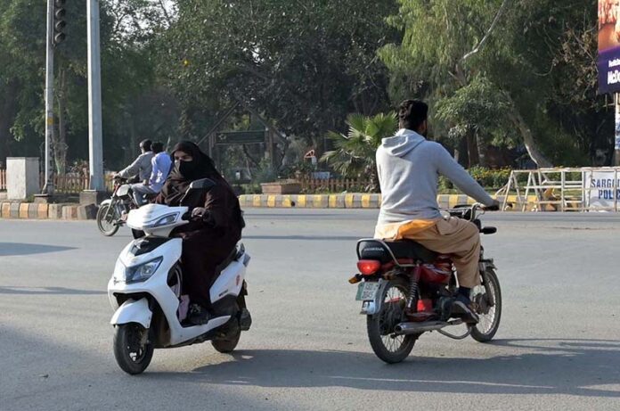 A woman on the way traveling on her scooty at college road