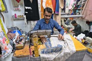 A worker busy in embroidery work on clothes at his workplace for customers as people starts preparation for the upcoming Eidul Fitr celebrations