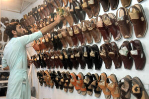 A shopkeeper busy in arranging and displaying footwear to attract the customer in the Provincial Capital.