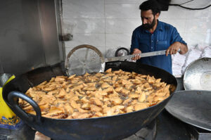 Workers busy in preparing traditional food item samosas before frying at their workplace during the Holy Month of Ramadan-ul-Mubarak