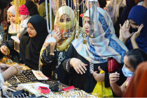 Lady police constable standing high alert during Women busy shopping in preparation for the upcoming Eid-ul-Fitr at Resham Gali Bazaar.