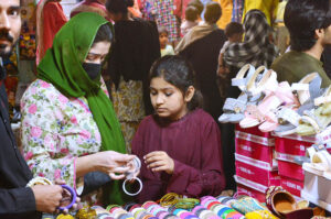 Lady police constable standing high alert during Women busy shopping in preparation for the upcoming Eid-ul-Fitr at Resham Gali Bazaar.