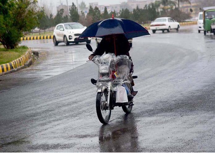 A motorcyclist on the way carrying an umbrella to protect from rain that experienced in the Provincial Capital