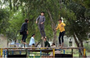 Children enjoy themselves by jumping on a trampoline set up by the roadside.