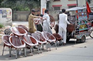 A vendor is busy arranging and displaying plastic-made chairs to attract the customers at his roadside setup