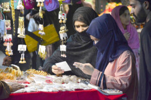 Women are selecting and purchasing artificial jewelry from a vendor in preparation for the upcoming Eidul Fitr at a local market.