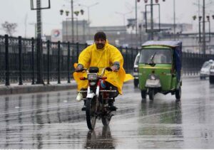 A motorcyclist on the way carrying an umbrella to protect from rain that experienced in the Provincial Capital