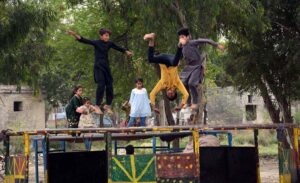 Children enjoy themselves by jumping on a trampoline set up by the roadside.