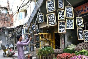 A vegetable vendor writes the prices of fresh vegetable on slates with chalk for customers outside his shop at Chowk Rustam Park