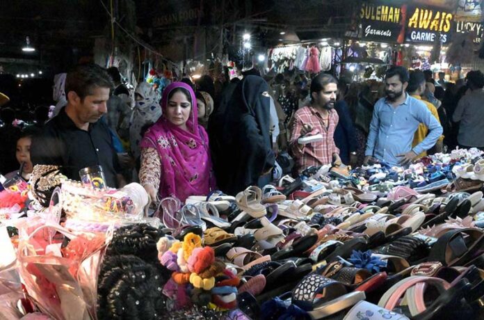 Women selecting and purchasing shoes from a vendor in preparation of the upcoming Eidul Fitr at Resham Bazaar