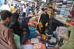 Women selecting and purchasing shoes from a vendor in preparation of the upcoming Eidul Fitr at Resham Bazaar