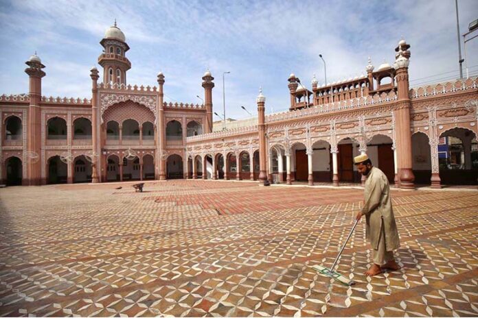 A volunteer diligently washes the floor of Sunehri Masjid before Namaz-e-Zohar during the holy month of Ramzan-ul-Mubarak