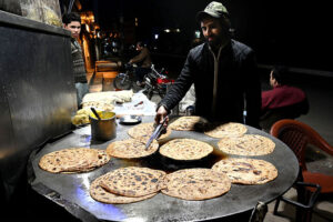 A vendor skillfully prepares crispy parathas for customers at a local market during the holy month of Ramzan-ul-Mubarak