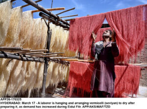 A laborer is hanging and arranging vermicelli (seviyan) to dry after preparing it, as demand has increased during Eidul Fitr.