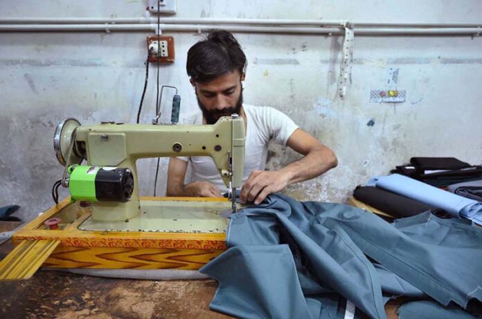 The tailor is occupied with sewing clothes for customers at his workplace in anticipation of the upcoming Eidul Fitr