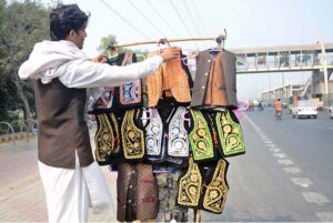 A vendor arranging and displaying traditional waist-coats for children to attract the customers along Gujumta Road