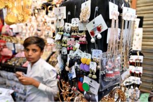 A young vendor displaying artificial jewelry to attract the customers in connection with upcoming Eid Ul Fitr at Resham Gali.