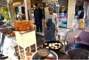 A vendor skillfully fries traditional food items to attract customers in the G-7 area of the Federal Capital during the holy month of Ramadan.