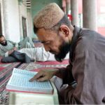 A person is engrossed in reciting the Holy Quran in Jamia Masjid Noori during holy fasting month of Ramadan