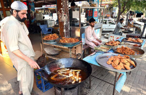 A vendor skillfully fries traditional food items to attract customers in the G-7 area of the Federal Capital during the holy month of Ramadan.