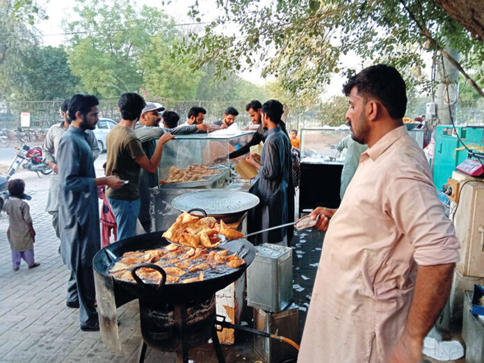 A man is frying samosas to sell at his roadside stall