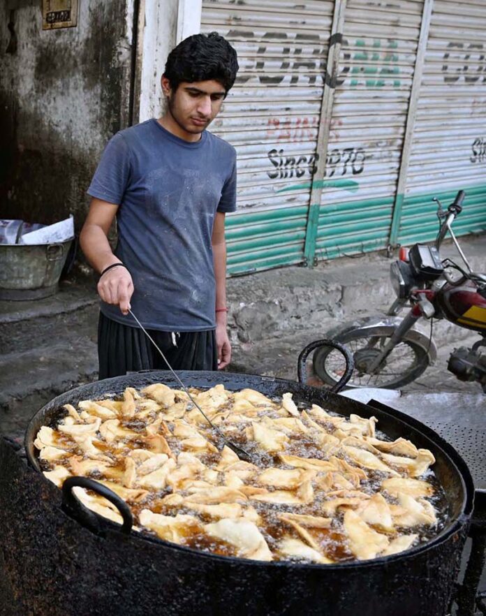 A vendor busy in frying traditional food stuff ‘samosa’ outside his shop during Holy Fasting Month of Ramzan