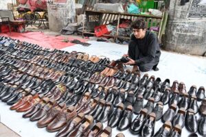 A vendor displaying shoes to attract the customers at his roadside setup.