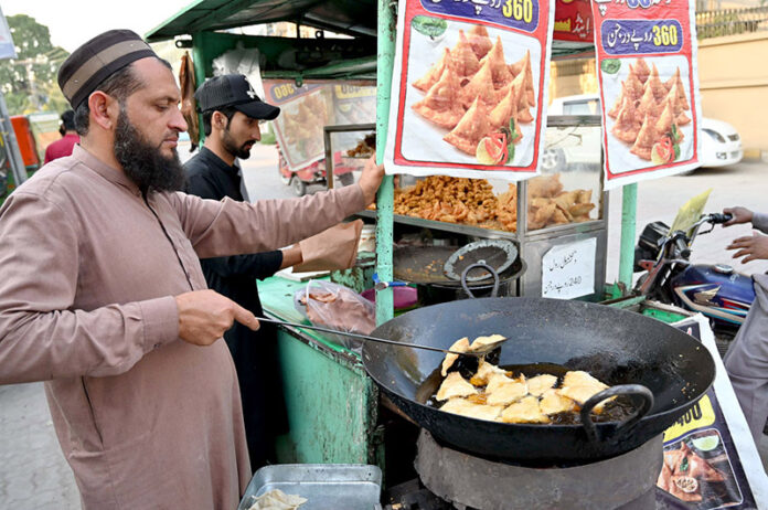 A street food vendor prepares samosas, a traditional food item for iftar, during the holy month of Ramadan