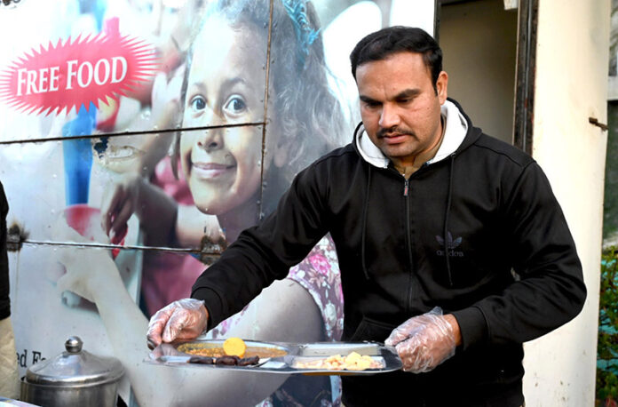 A worker serves free food to people in fasting during Iftar arranged by Umeed Food Trust at G-8 in the federal capital