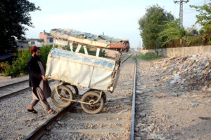 A man crossing a cart through the railway track of the Kot Lakhpat railway line towards his destination