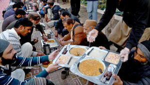 A worker serves free food to people in fasting during Iftar arranged by Umeed Food Trust at G-8 in the federal capital