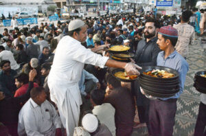 Volunteers distributing food among people to break their fast at roadside setup arrange by philanthropists during holy fasting month of Ramadan.