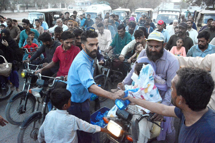 A man distributing Iftari among the commuters near Mazar e Quaid