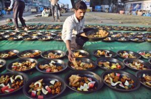 Volunteers distributing food among people to break their fast at roadside setup arrange by philanthropists during holy fasting month of Ramadan.