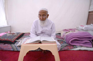 An aged man is reciting the Quran at Sunehri Masjid during Itikaf an Islamic meritorious voluntary practice of secluding oneself in a mosque for a period of time, dedicating it to worship and spiritual reflection, typically during Ramadan