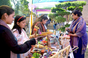 Women look at handmade item on display at a stall in Al-Hamr Hall on the occasion of International Women's Day.