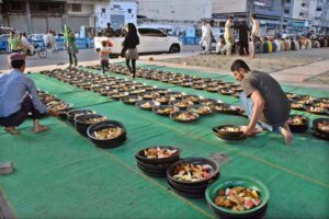 Volunteers distributing food among people to break their fast at roadside setup arrange by philanthropists during holy fasting month of Ramadan.